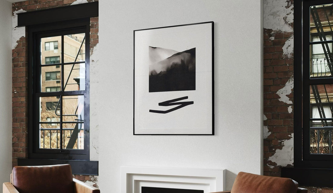 Contemporary, black and white, abstract framed print of mountains and geometric line underneath, installed above a fireplace in a converted loft space